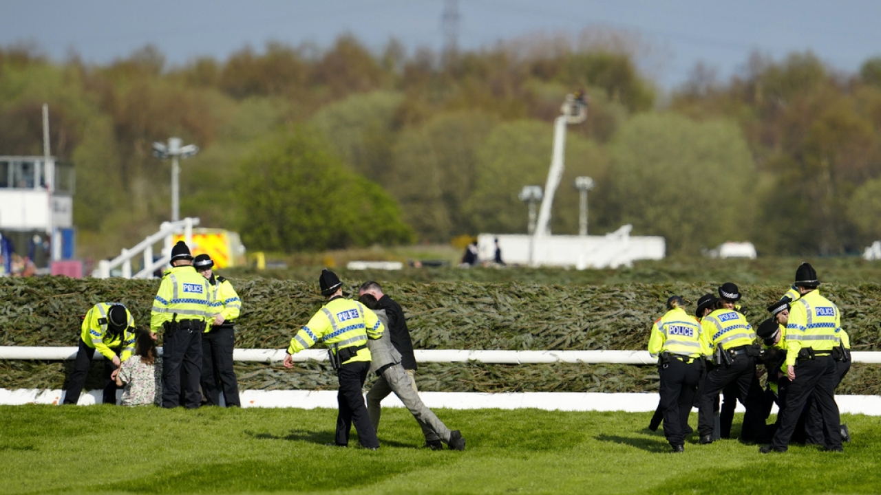 Members of the police forces remove protesters as they tried to block the start of the Grand National horse race.