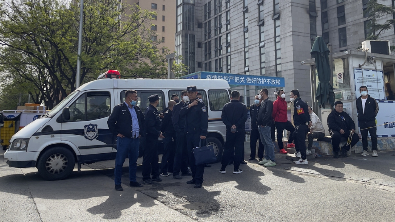 Police officers and security guards gather outside the barricaded hospital following a fire at a hospital in Beijing.