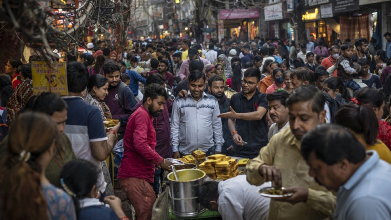 People eat street food as shoppers crowd a market in New Delhi.