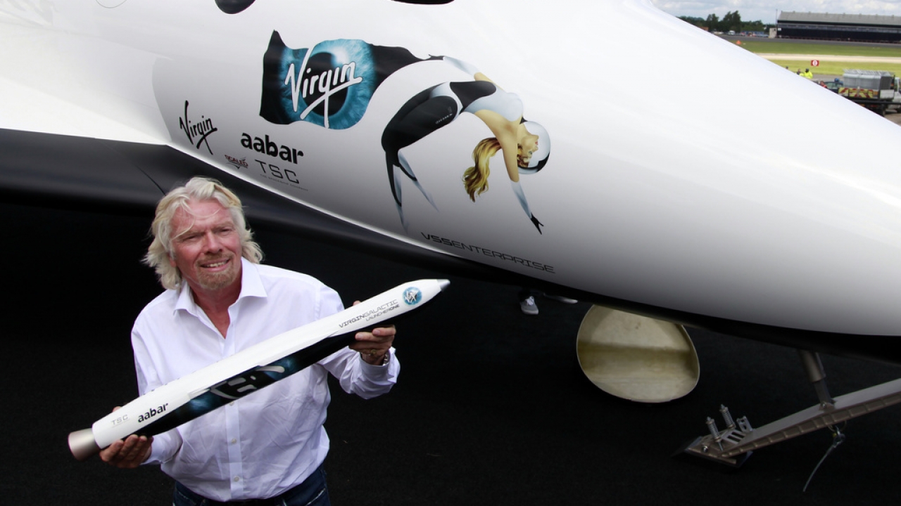 Richard Branson poses with a model of the LauncherOne rocket.