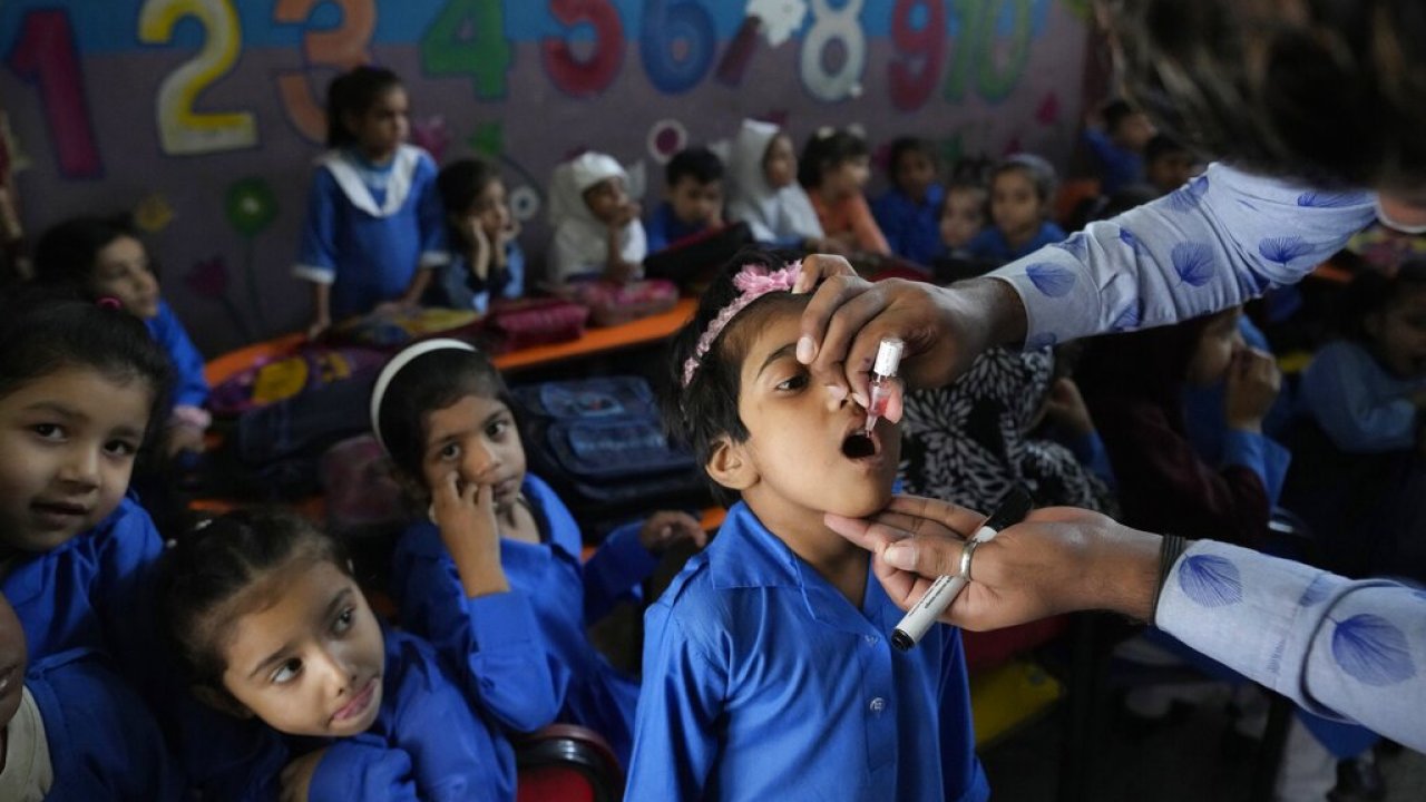 A health worker administers a polio vaccine to a child at a school in Lahore, Pakistan.