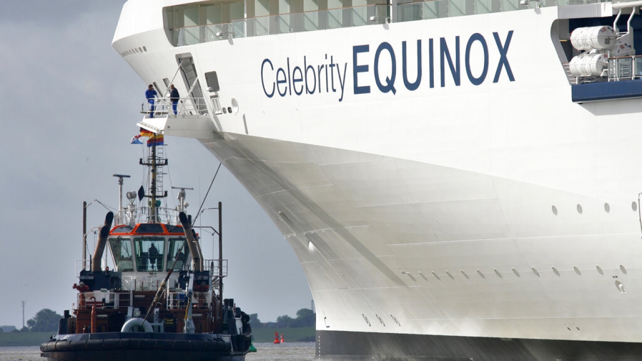 A tug boat is seen in front of the cruiser Celebrity Equinox.