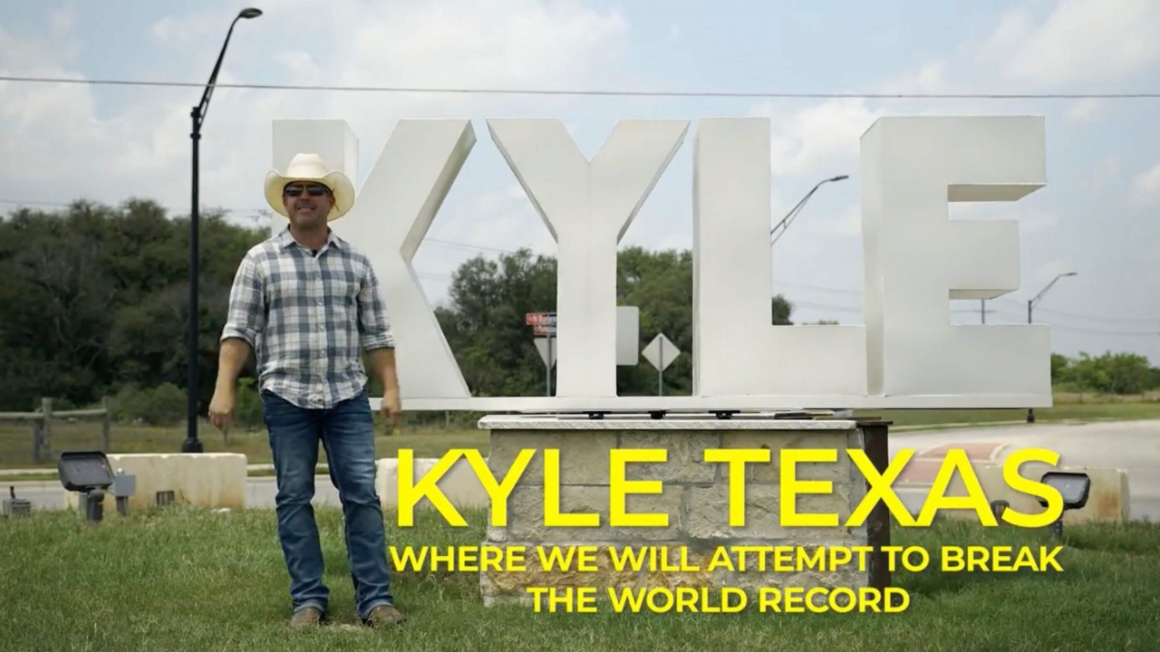 A man stands next to a "Kyle" sign.