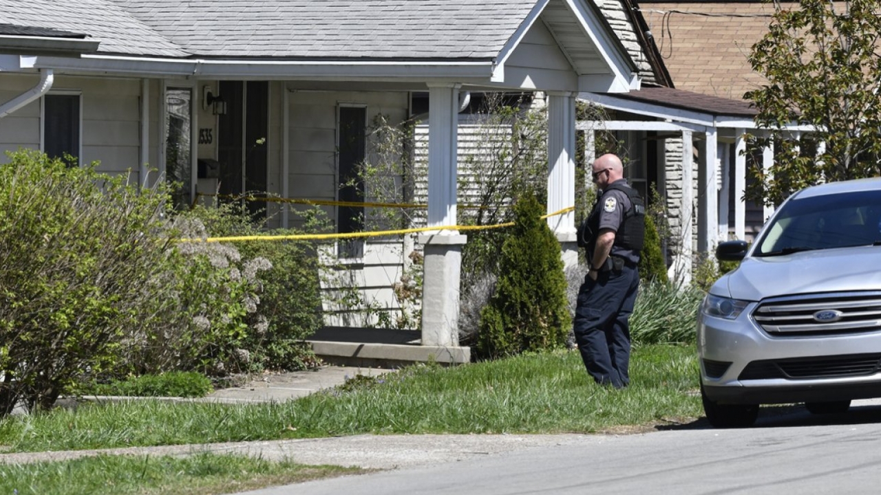 A Louisville Metro Police officer walks outside of the home of a suspected shooter