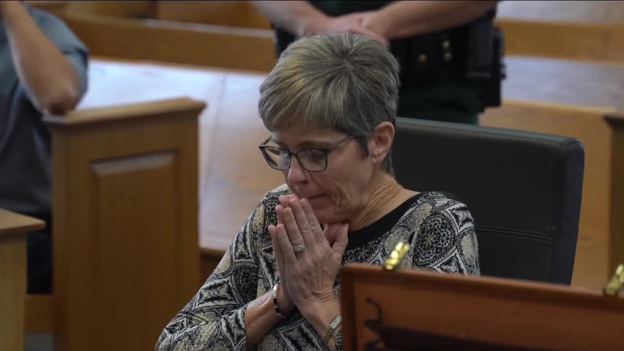 Tracey Nix looks down in court as she holds her hands together by her face.