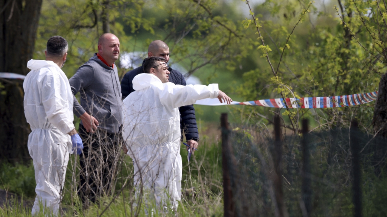 Forensic police inspects the scene around a car in the village of Dubona in Serbia.