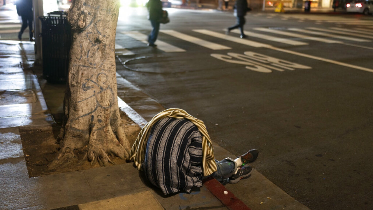 A homeless person sleeps on a sidewalk in Los Angeles.