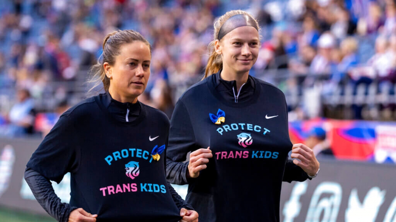 OL Reign defender Lauren Barnes and forward Bethany Balcer display shirts that read "Protect Trans Kids" before soccer match.