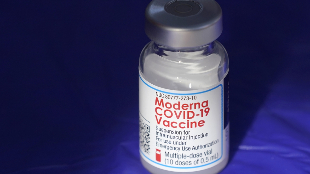 A vial of the Moderna COVID-19 vaccine rests on a table.