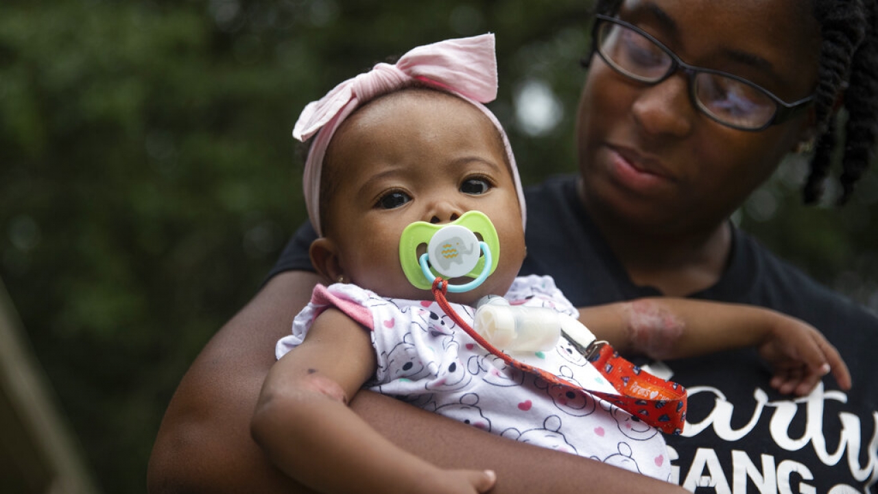 Tyesha Young holds her 7-month-old baby Jalayah Johnson outside their home.