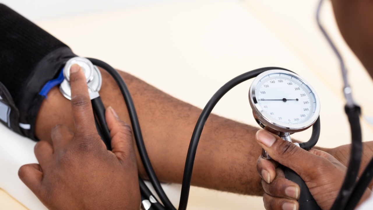 Doctor conducts blood pressure screening on Black patient.