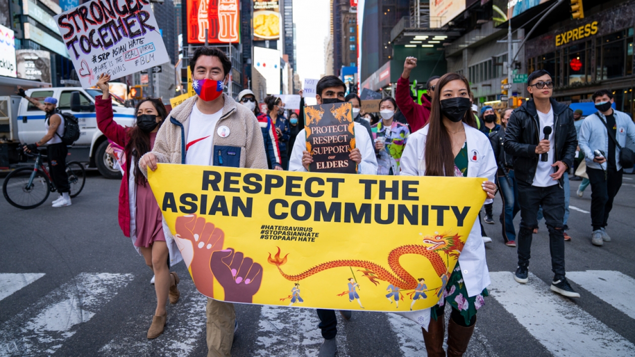 Several people hold a banner that reads "respect the Asian community" in Times Square.