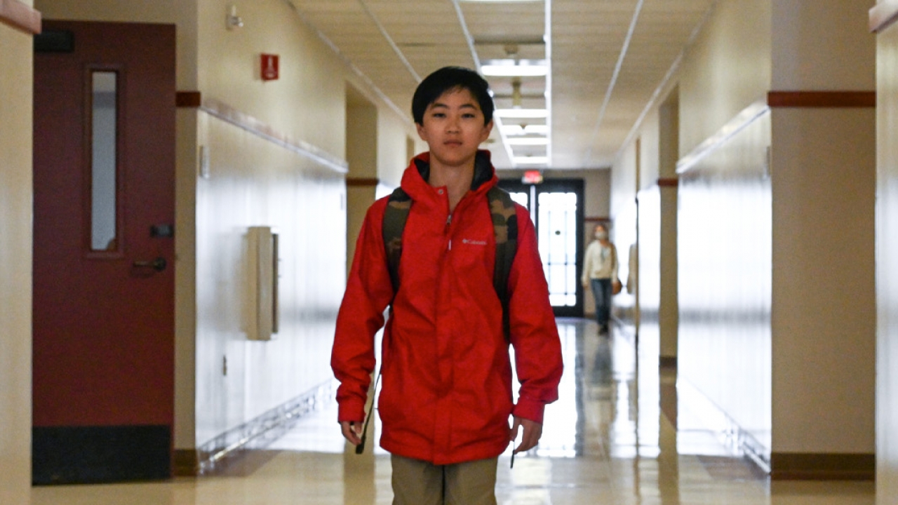 12-year-old Clovis Hung walks down a school hallway.
