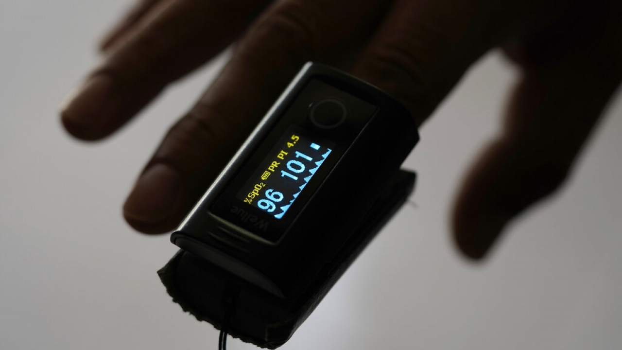 A man checks his device to monitor his blood oxygen level.