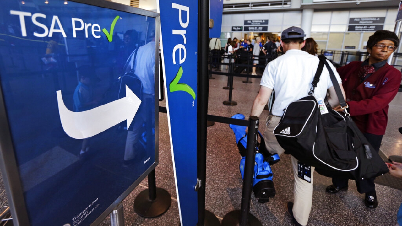 Travelers go through a TSA PreCheck screening line at an airport.