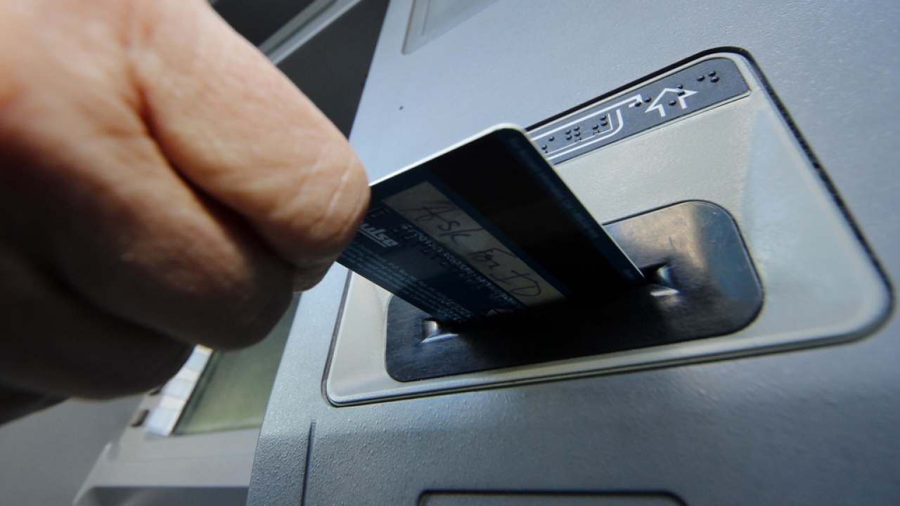A person inserts a debit card into an ATM.