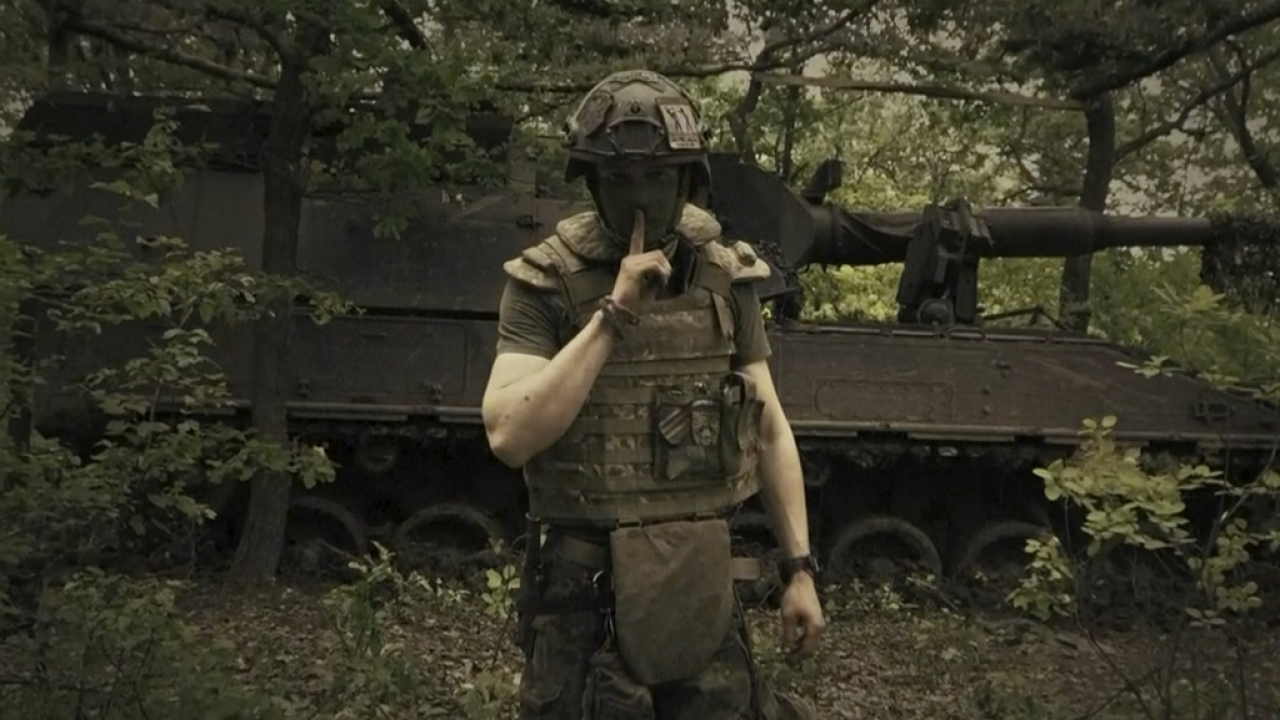 Ukrainian soldier poses for the camera with his fingers to his lips.