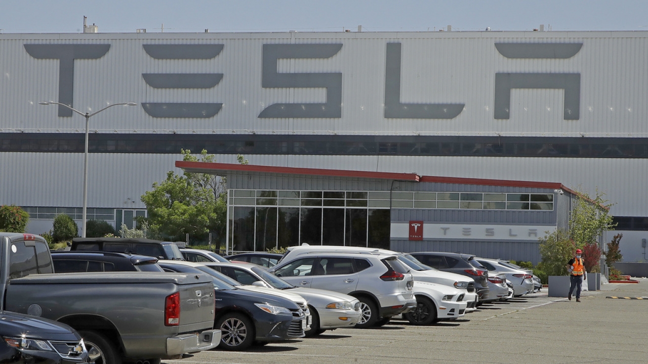 A man walks in the Tesla plant parking lot.