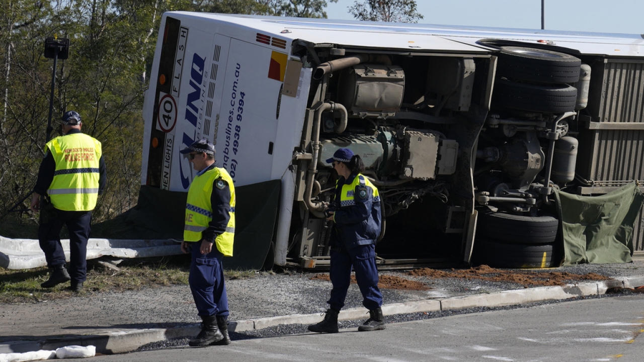 Police inspect a bus on its side after a crash in Australia