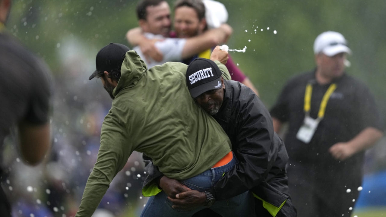 Canadian professional golfer Adam Hadwin, left, is stopped by a security guard while he tries to celebrates with Nick Taylor.