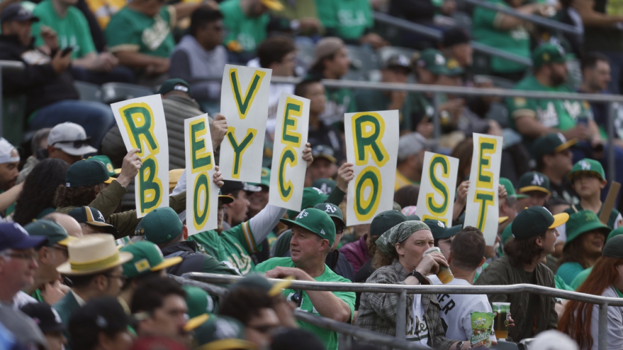 Fans hold signs inside of the Oakland Coliseum to protest the Oakland Athletics' planned move to Las Vegas.