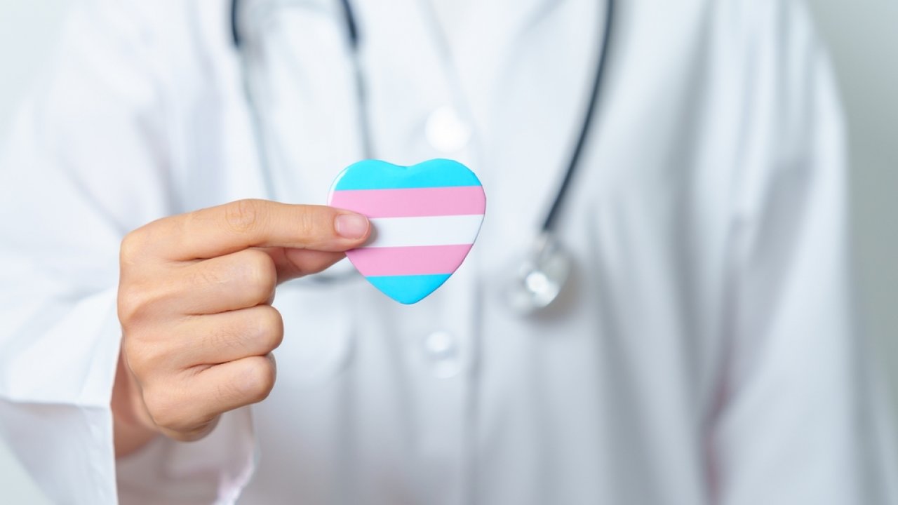 A doctor with a heart featuring the transgender flag.
