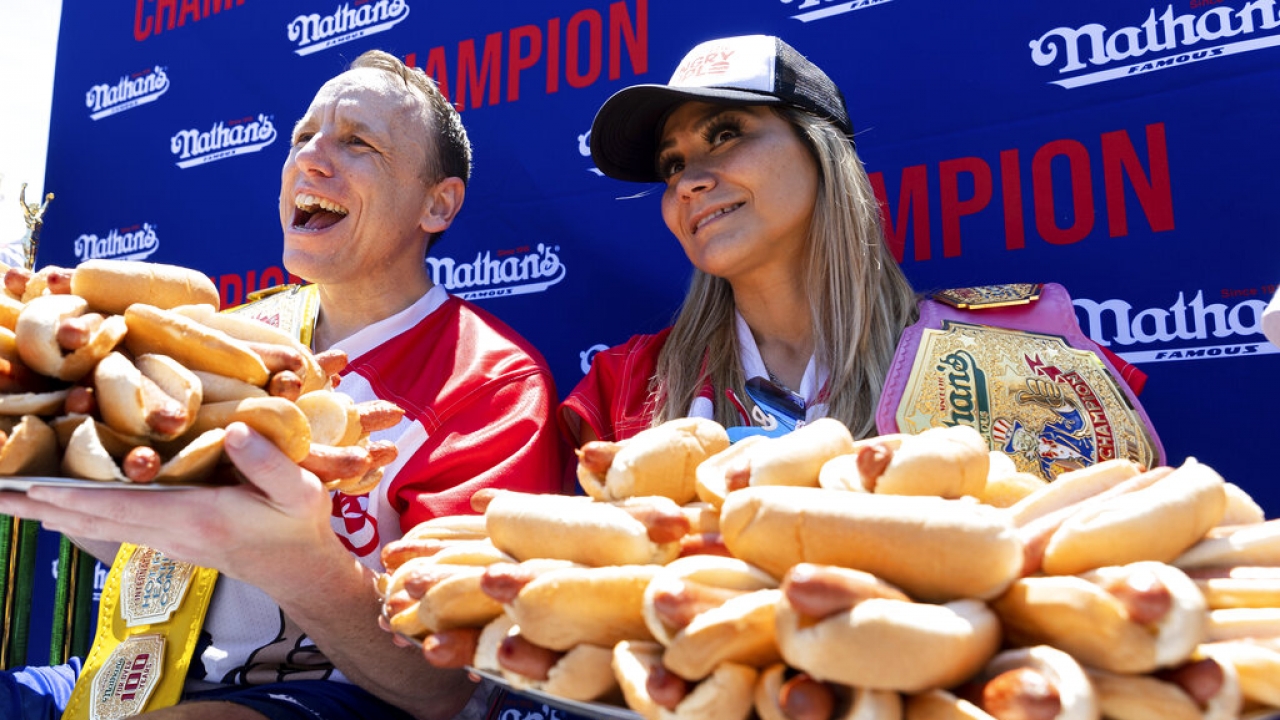 Joey Chestnut and Miki Sudo pose with hot dogs during the Nathan's Famous Hot Dog Eating Contest.