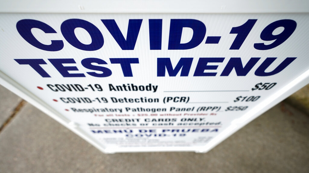 A sign outside Principle Health Systems and SynerGene Laboratory lists COVID-19 tests.