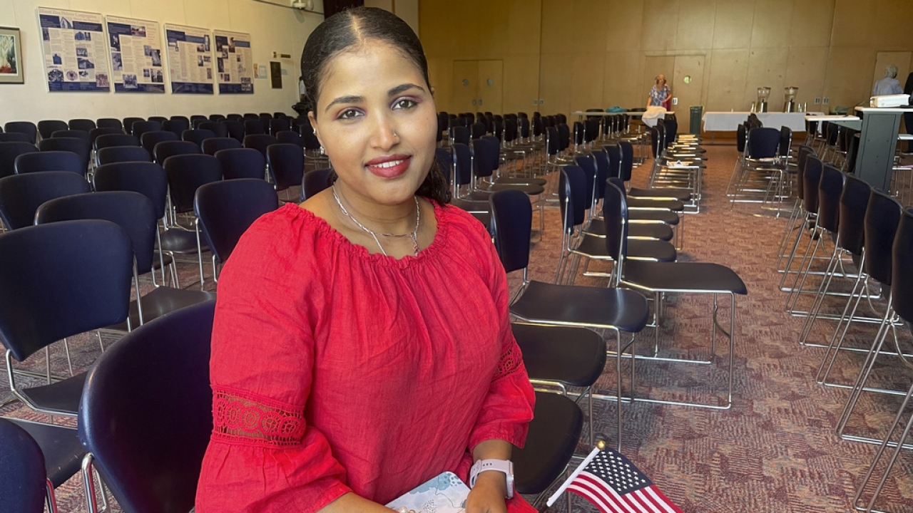 A woman smiles and holds a small American flag after becoming a U.S. citizen.