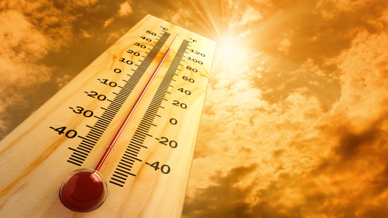 Photo illustration of a thermometer under a hot sun.