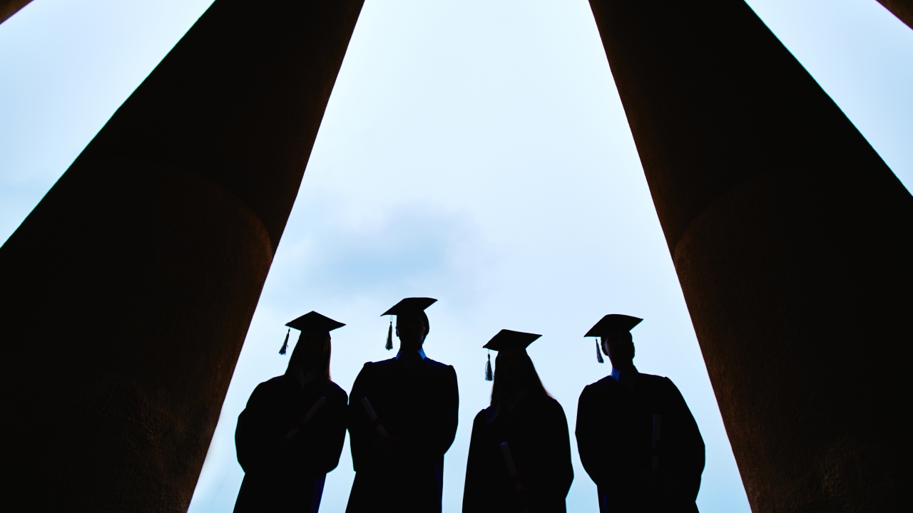 Silhouettes of graduates wearing caps and gowns.