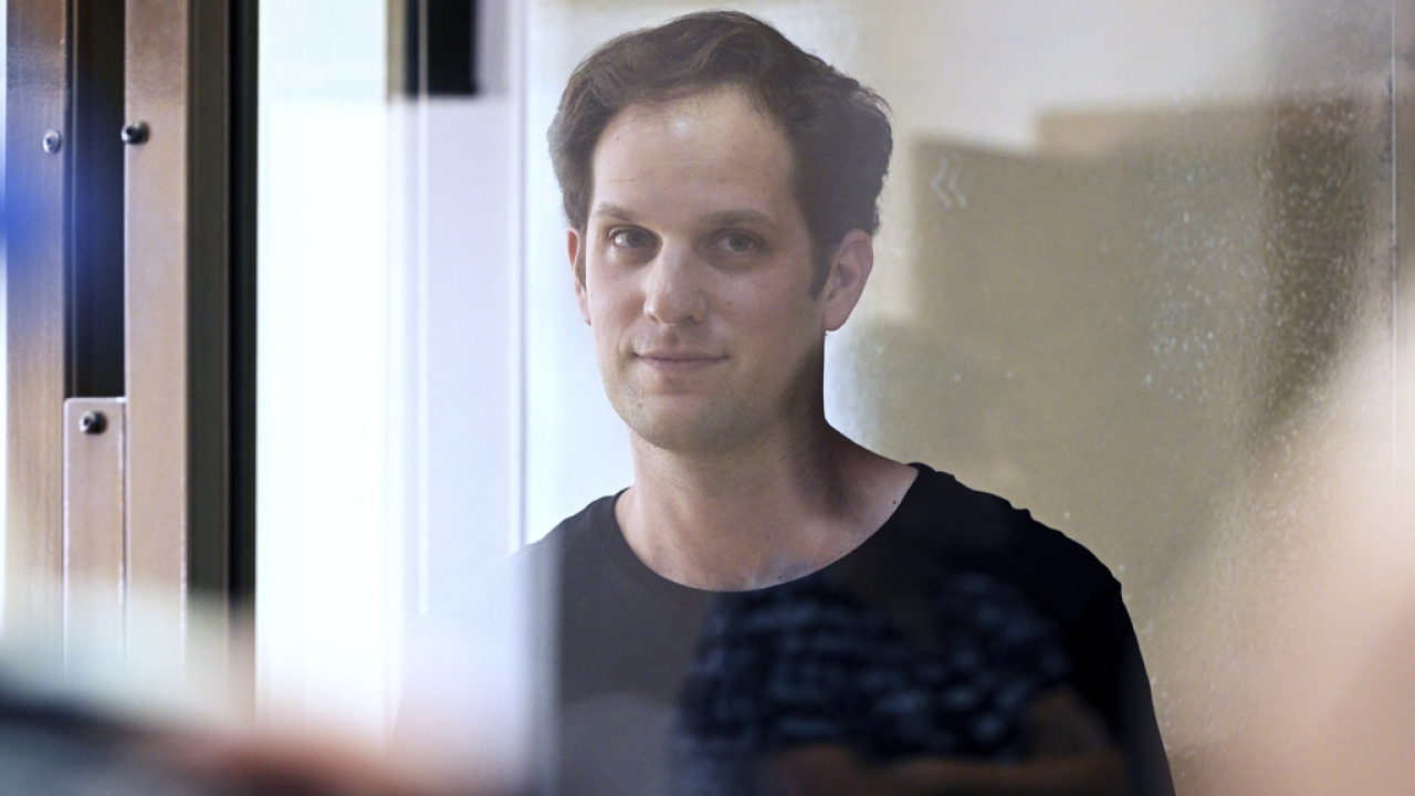 Wall Street Journal reporter Evan Gershkovich stands in a glass cage in a courtroom