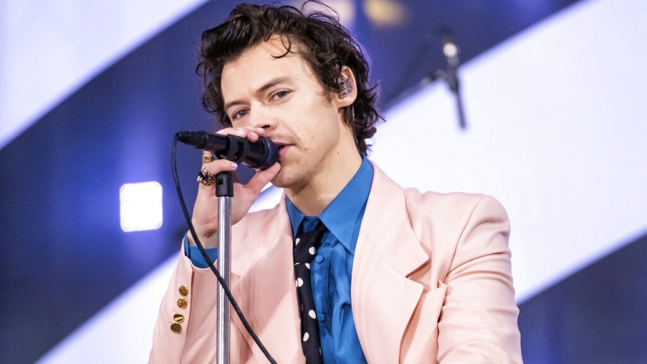 Harry Styles sings into a microphone on stage
