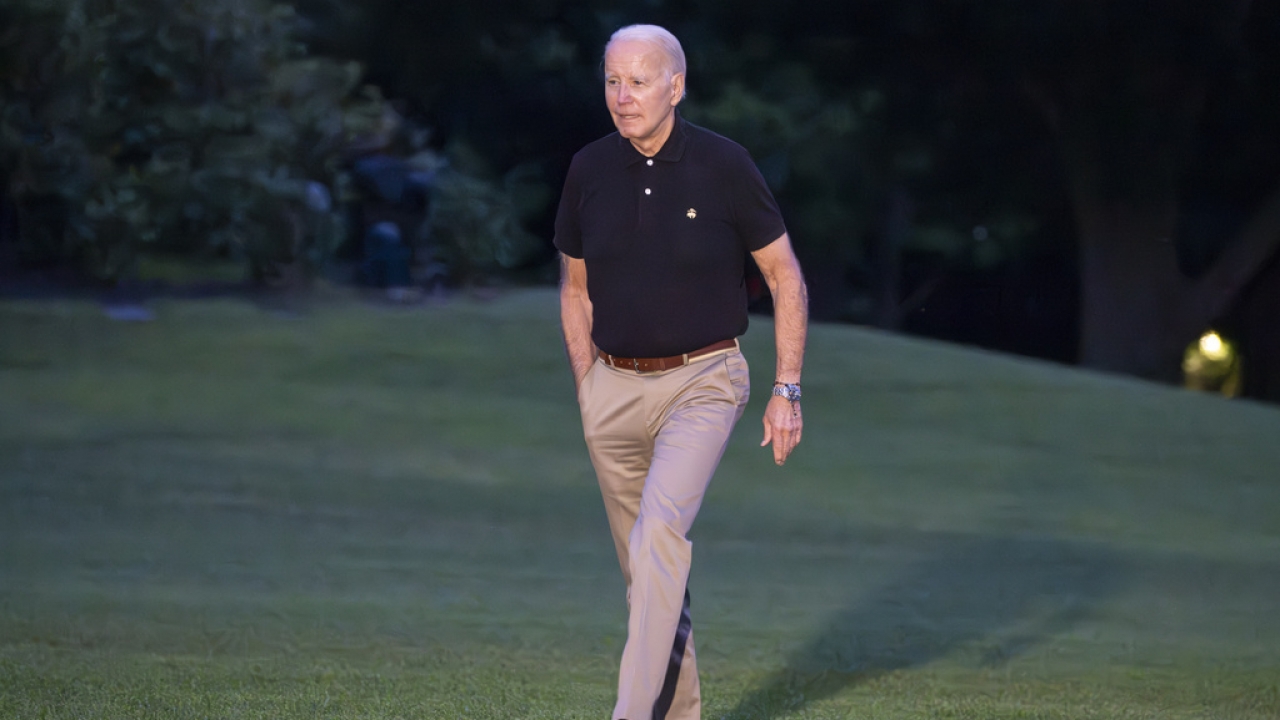 President Joe Biden walks on a lawn.