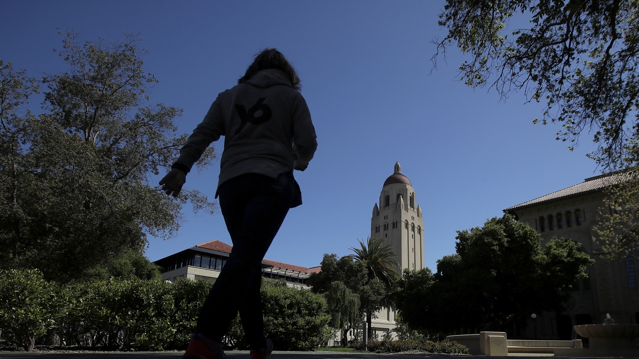 People walk on the Stanford University campus beneath Hoover Tower in Stanford, Calif.