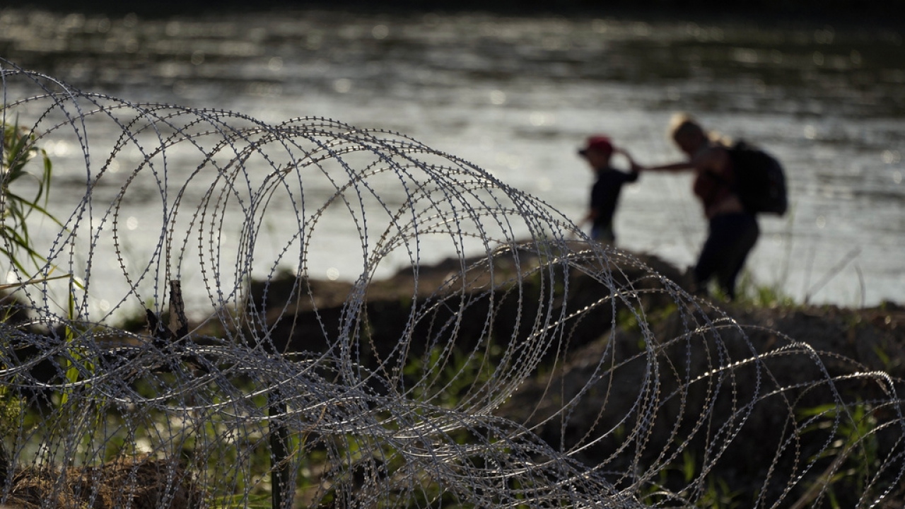 Migrants walk along concertina wire as they try to cross the Rio Grande at the Texas-U.S. border.