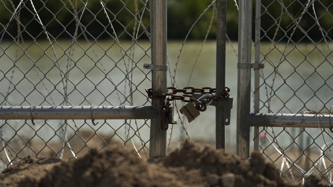 A fence lined with concertina wire along the Rio Grande.