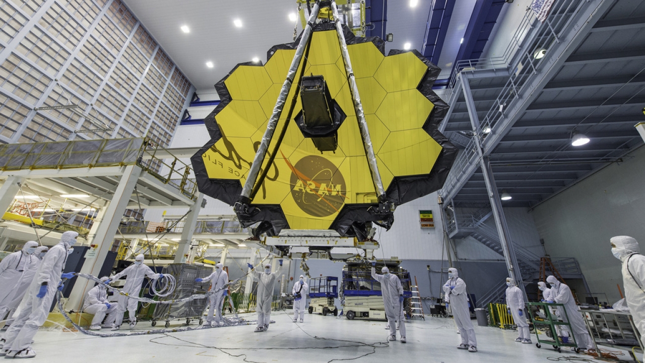 Technicians lift the mirror of the James Webb Space Telescope using a crane.
