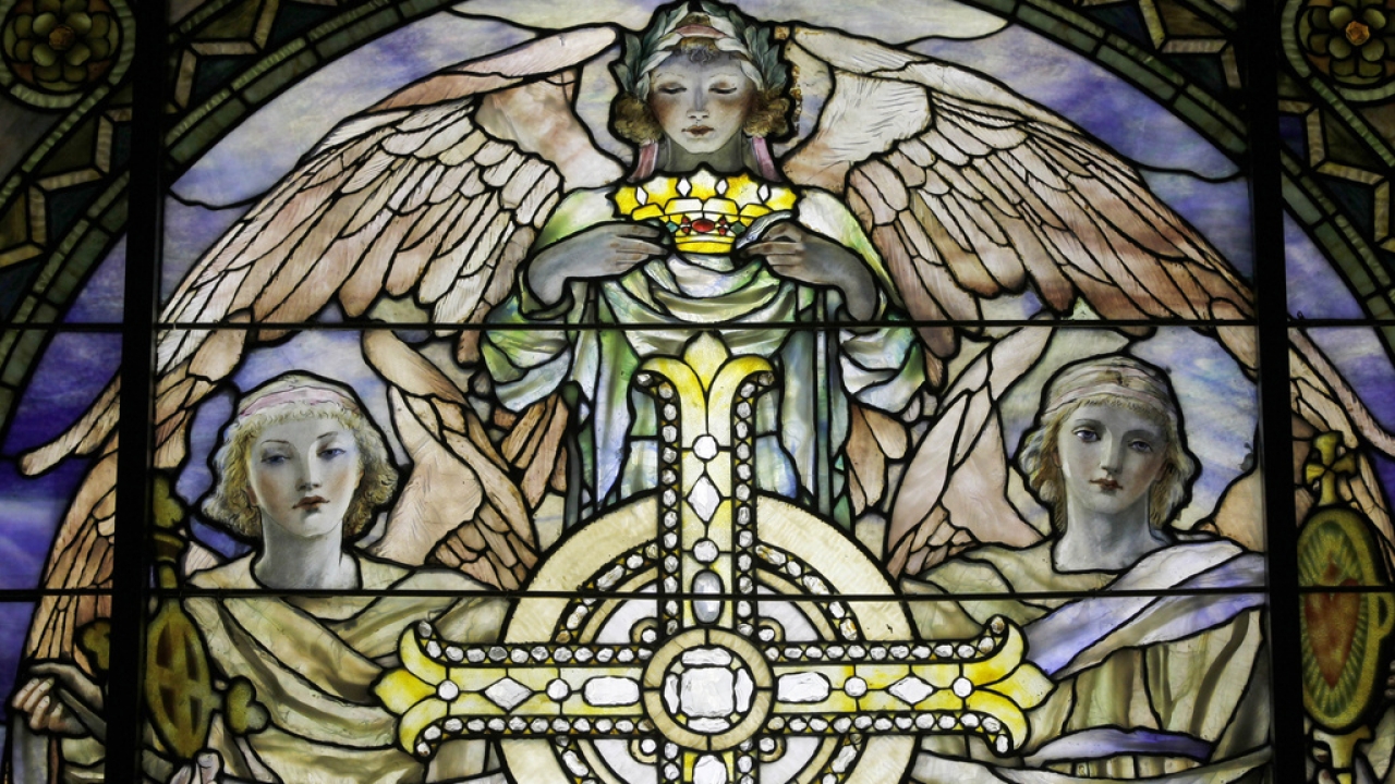 Details of angels surrounding a cross in a stained glass church window
