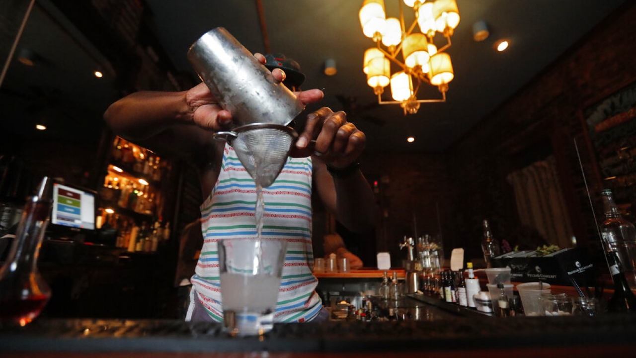 Bartender pours a cocktail through a strainer.