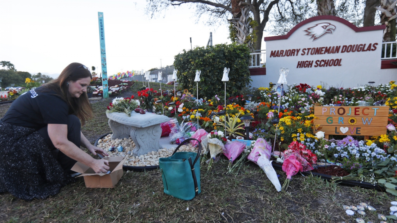 A person lays items outside a memorial at Marjory Stoneman Douglas High School.
