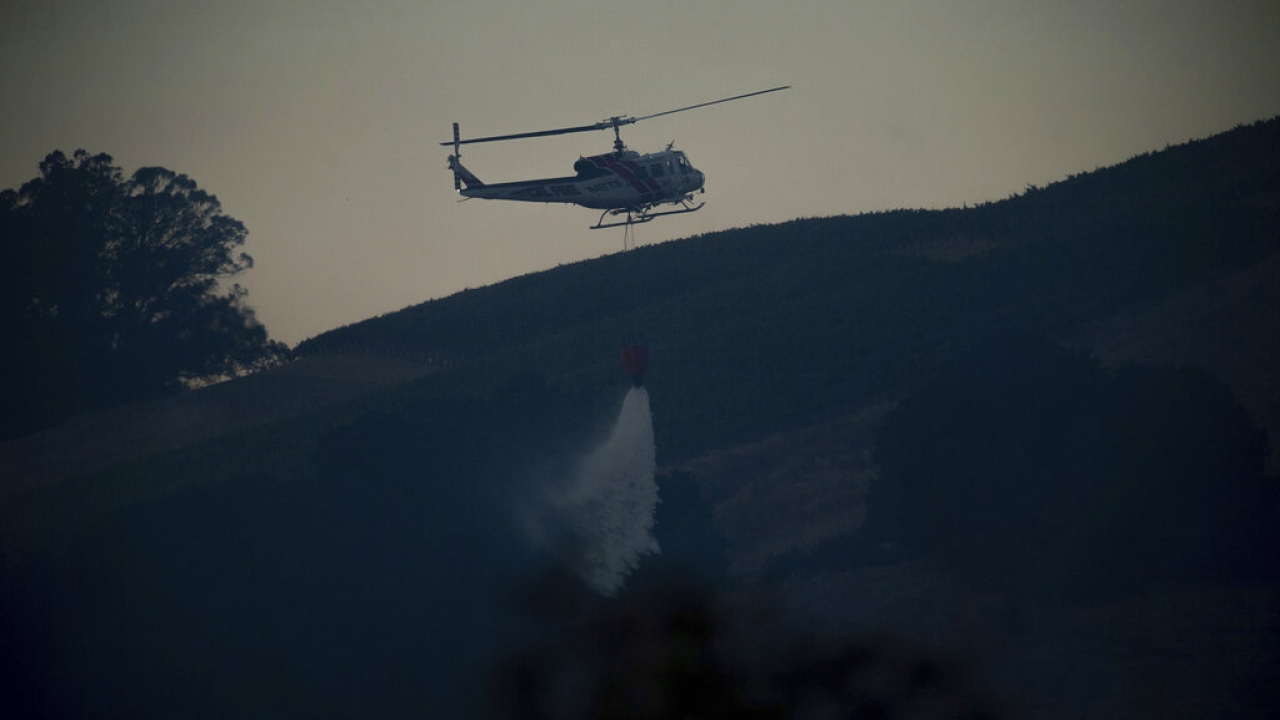 A helicopter drops water while fighting a wildfire.