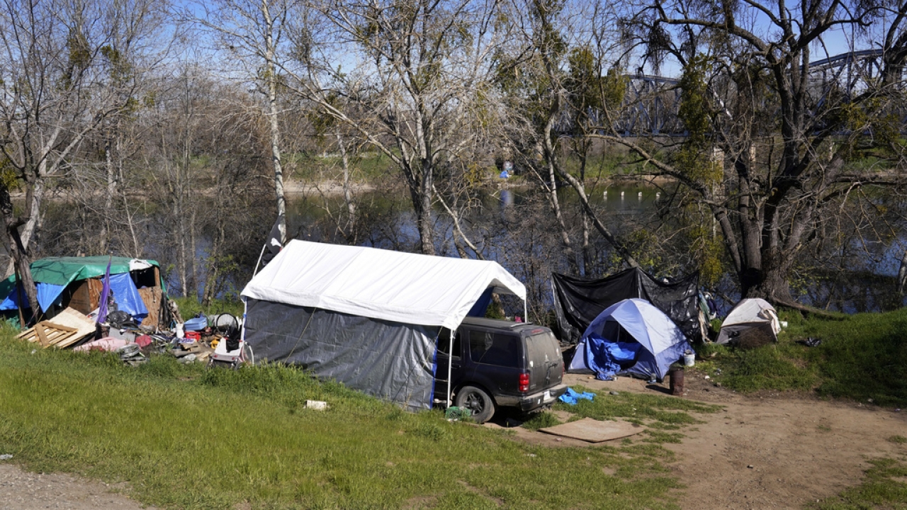 Tents and other shelters used by people experiencing homelessness stand along the American River Parkway in Sacramento.