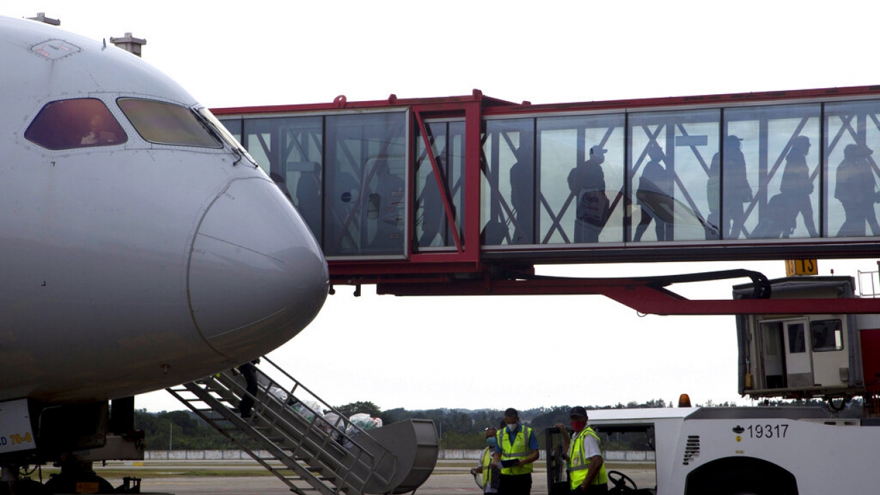 People line up on a jet bridge to board a plane