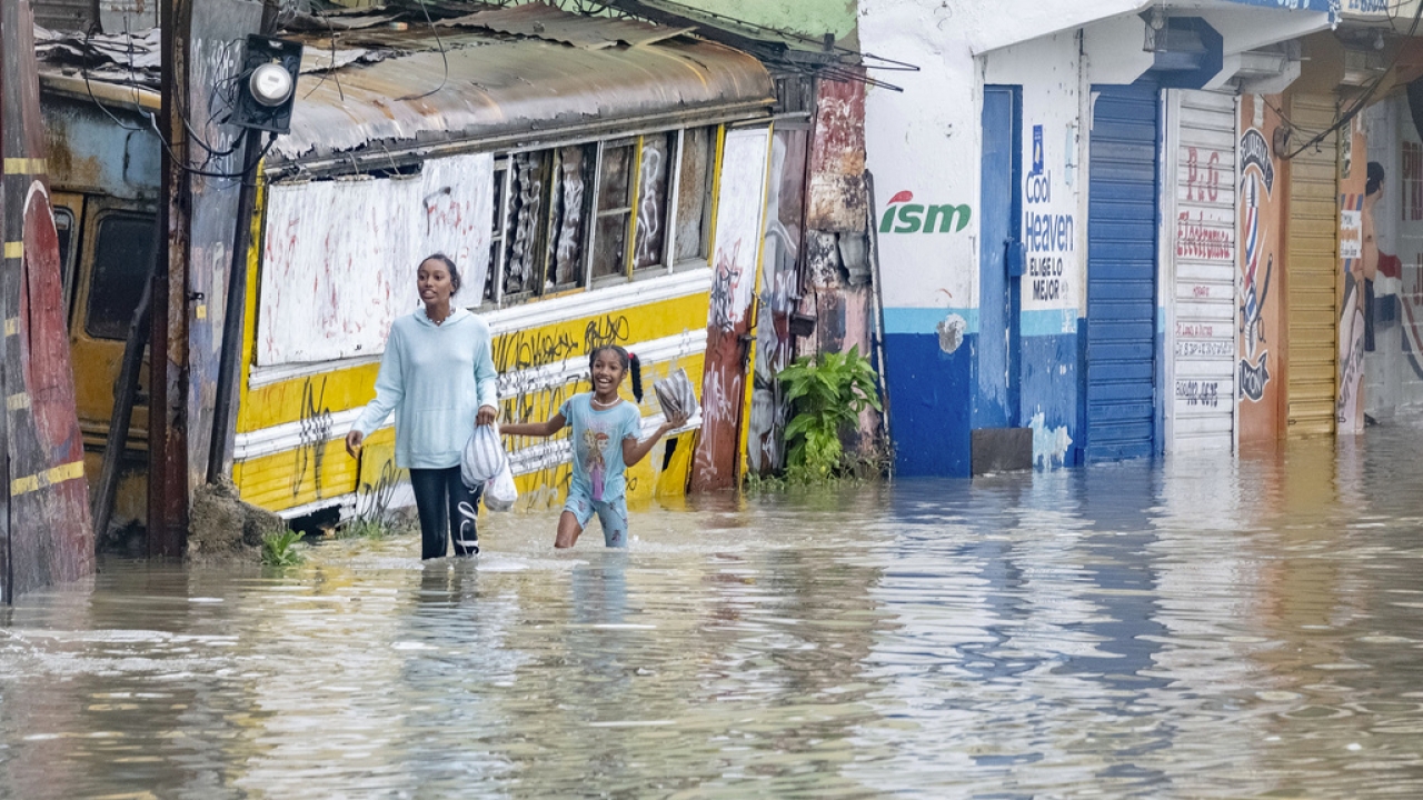People walk through a street flooded by the rains of Tropical Storm Franklin in Santo Domingo, Dominican Republic