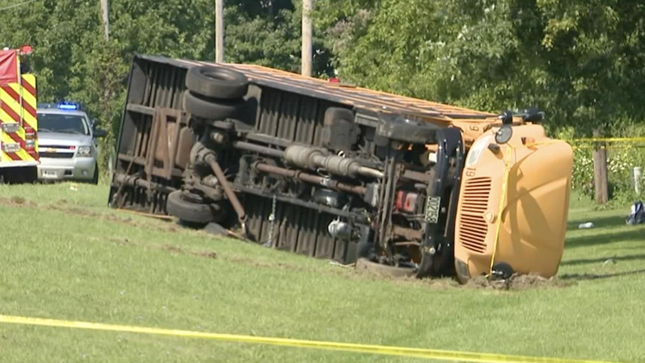 A school bus on its side after striking an oncoming vehicle.