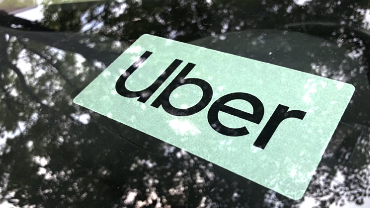 Uber's logo is shown in a car window.