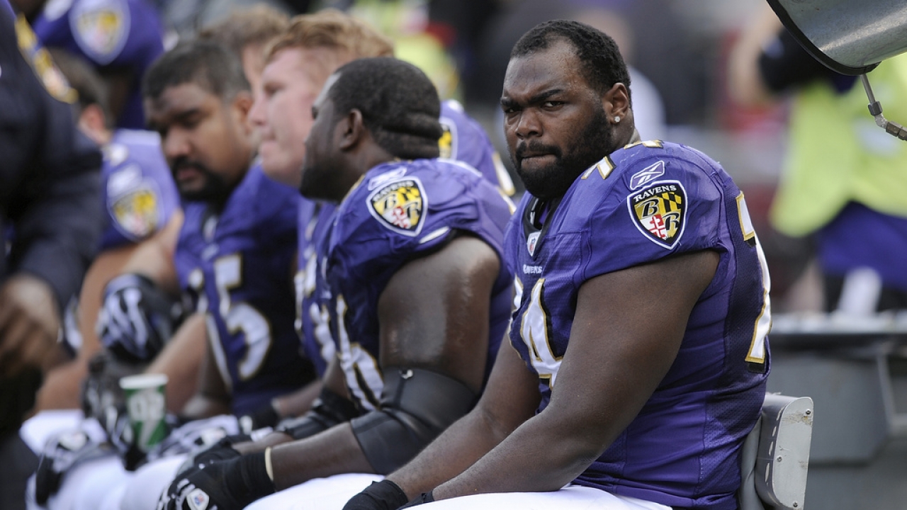 Michael Oher sits on the football bench.