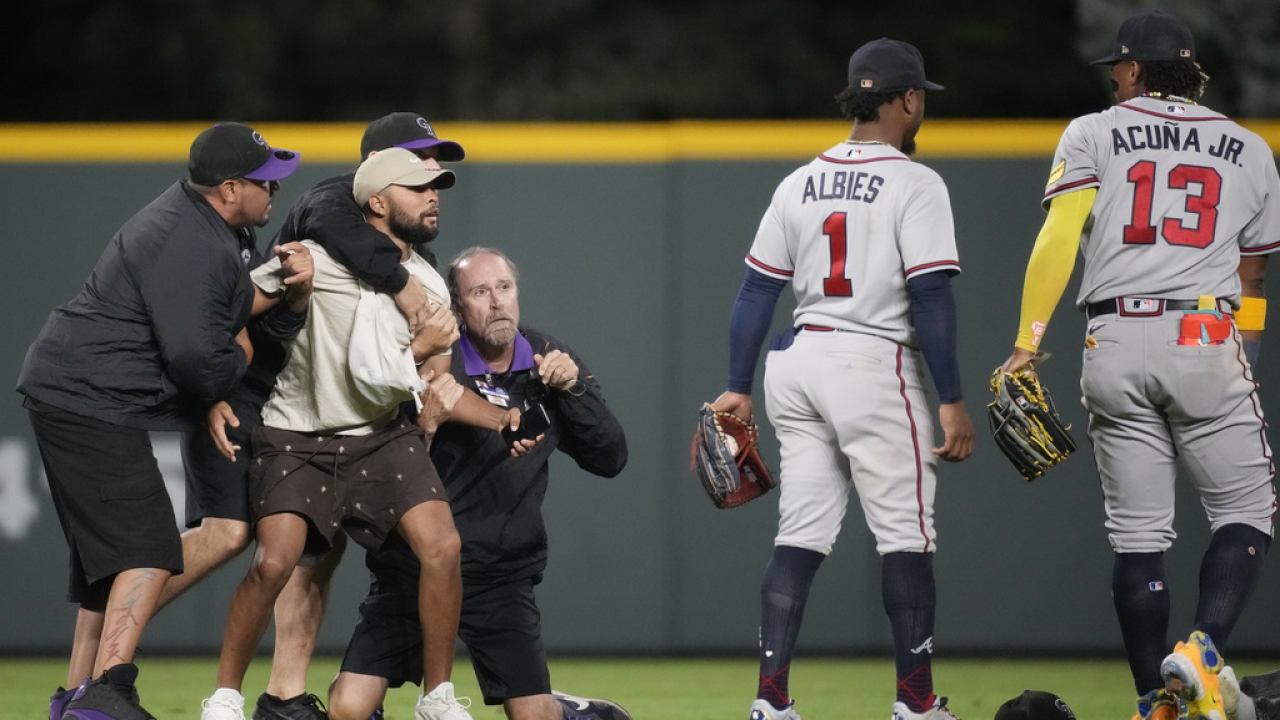 A fan is restrained after apparently trying to take a picture with Atlanta Braves outfielder Ronald Acuña Jr. during a game.