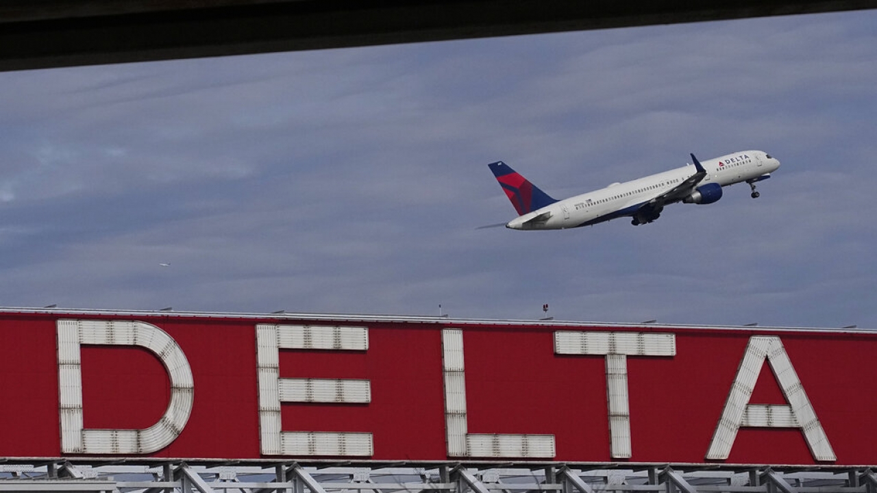Delta airplane flies over a Delta sign